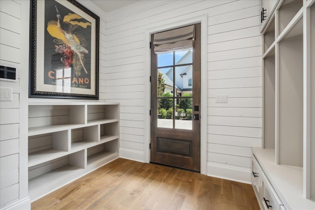 mudroom with light wood-type flooring and wooden walls