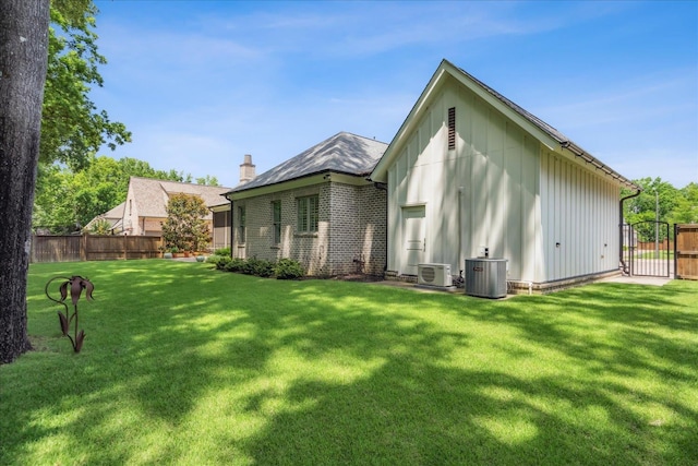 rear view of house featuring central AC unit, a lawn, and ac unit