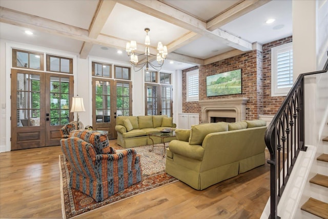 living room with a healthy amount of sunlight, french doors, brick wall, and an inviting chandelier