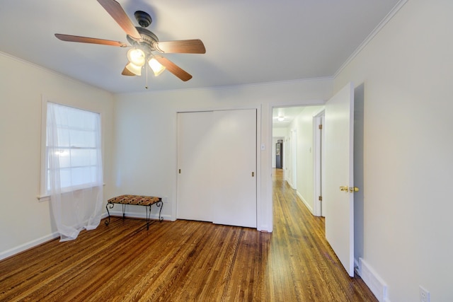 unfurnished bedroom featuring dark wood-type flooring, crown molding, baseboards, and a ceiling fan