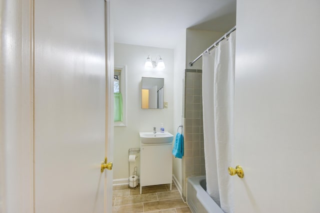 bathroom with shower / bath combo, a sink, and baseboards