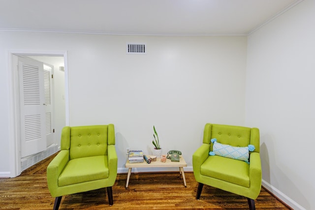 living area featuring visible vents, crown molding, baseboards, and wood finished floors