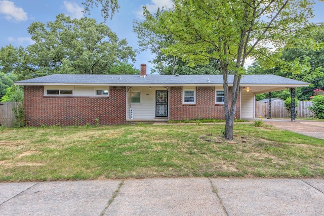 single story home featuring brick siding, concrete driveway, a front yard, fence, and a carport