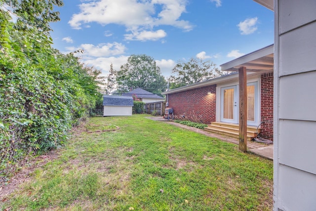 view of yard with entry steps, a storage unit, an outbuilding, and fence