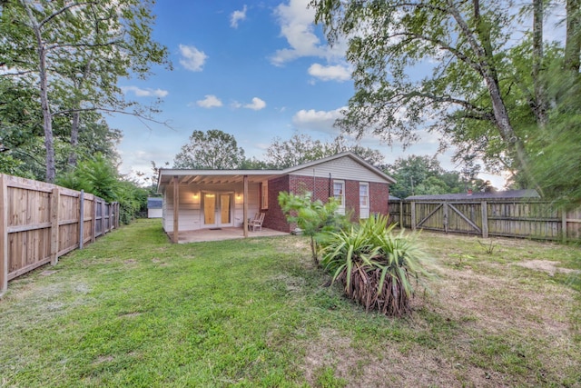 back of house featuring brick siding, a yard, a patio, a gate, and a fenced backyard