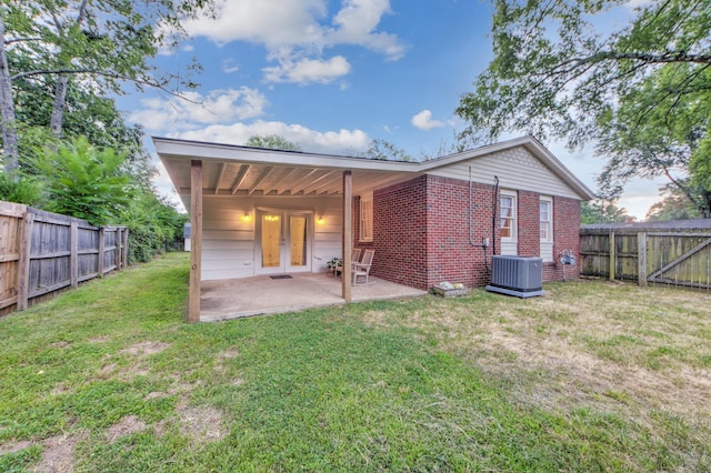 rear view of property with a patio, a fenced backyard, brick siding, french doors, and a lawn