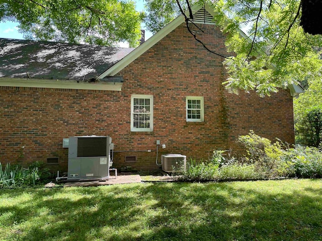 back of property featuring a lawn and central air condition unit