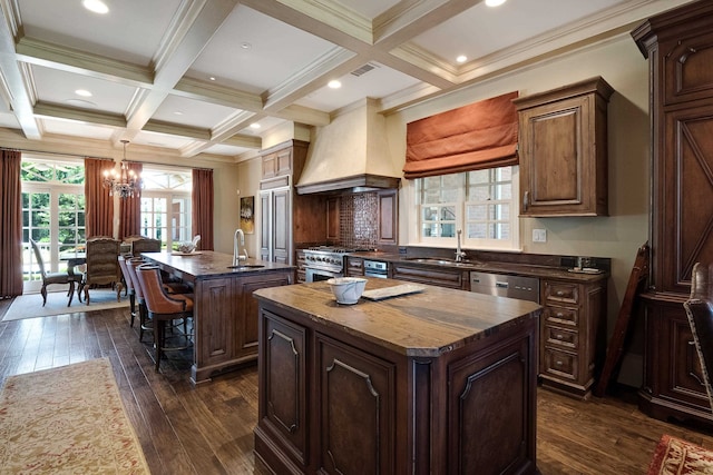 kitchen with coffered ceiling, custom exhaust hood, dark hardwood / wood-style flooring, and a center island with sink