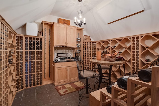 wine room featuring vaulted ceiling, dark tile patterned floors, and a notable chandelier