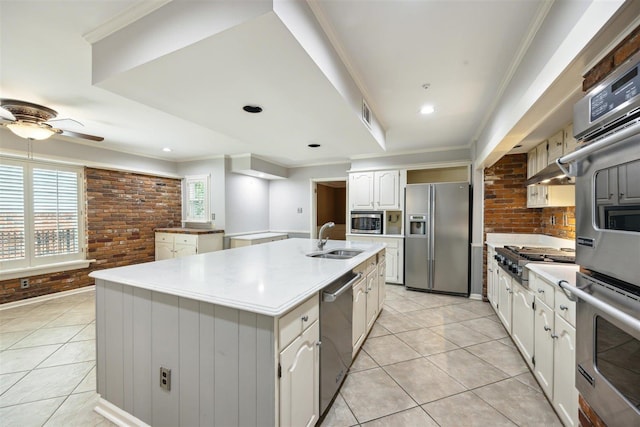 kitchen featuring appliances with stainless steel finishes, sink, white cabinets, light tile patterned floors, and a center island with sink