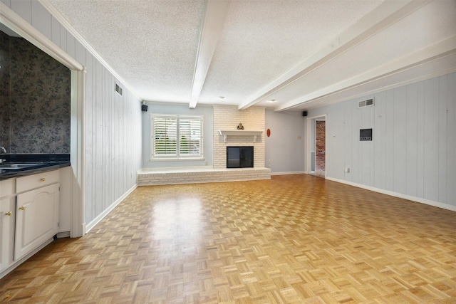 unfurnished living room with beamed ceiling, light parquet floors, a fireplace, and wood walls