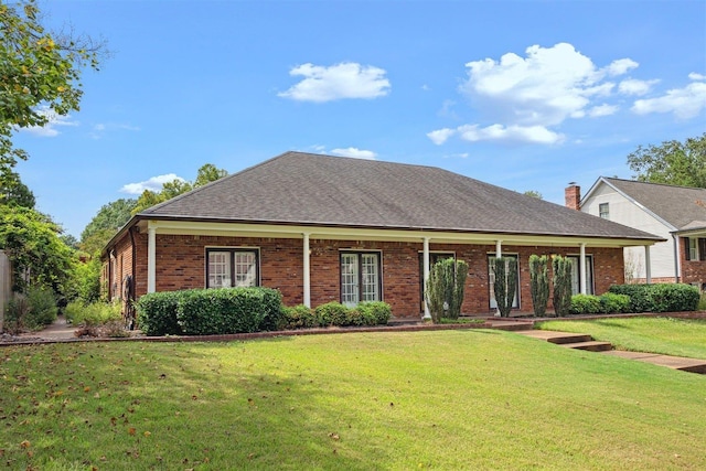 view of front facade with a front yard, brick siding, and roof with shingles