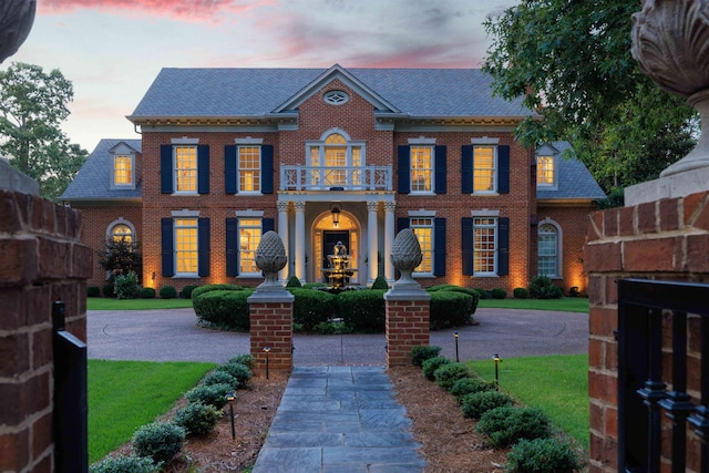 colonial home featuring brick siding and a balcony