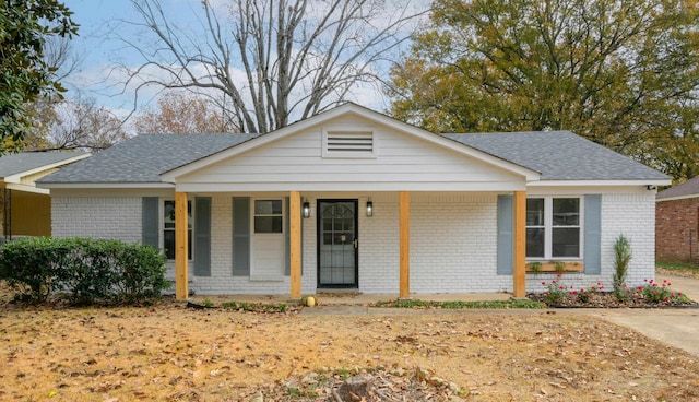 view of front of home with a porch, a shingled roof, and brick siding