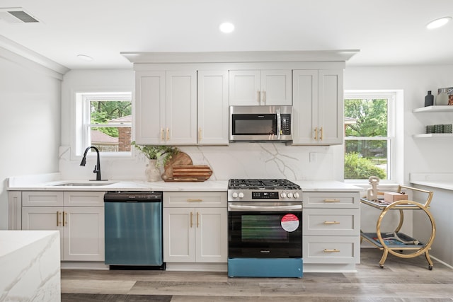 kitchen with recessed lighting, light stone counters, decorative backsplash, appliances with stainless steel finishes, and a sink