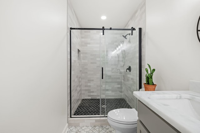 bathroom featuring a shower with shower door, vanity, tile patterned floors, and toilet