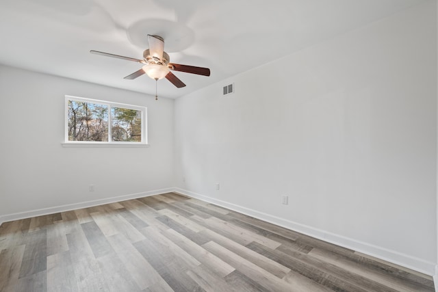 spare room with visible vents, ceiling fan, wood finished floors, and baseboards