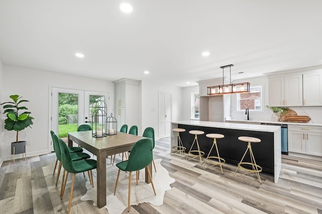 dining room with sink, plenty of natural light, french doors, and light wood-type flooring