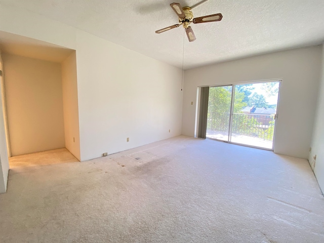 empty room featuring a textured ceiling, ceiling fan, and light colored carpet