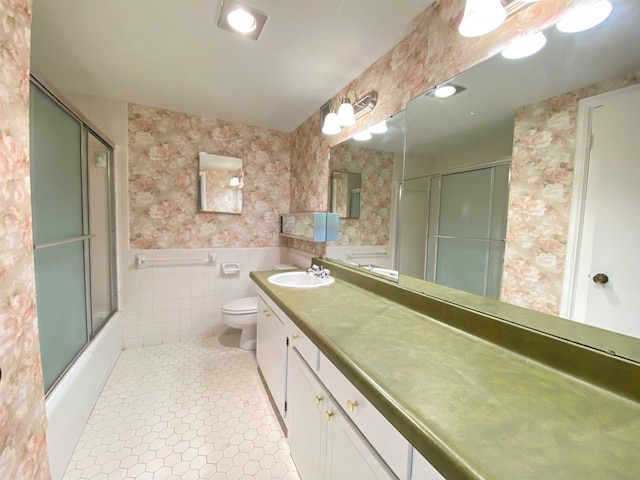 full bathroom with vanity, tile patterned floors, tile walls, combined bath / shower with glass door, and toilet