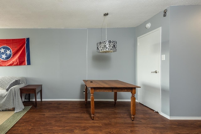 dining area featuring dark wood-type flooring and a textured ceiling