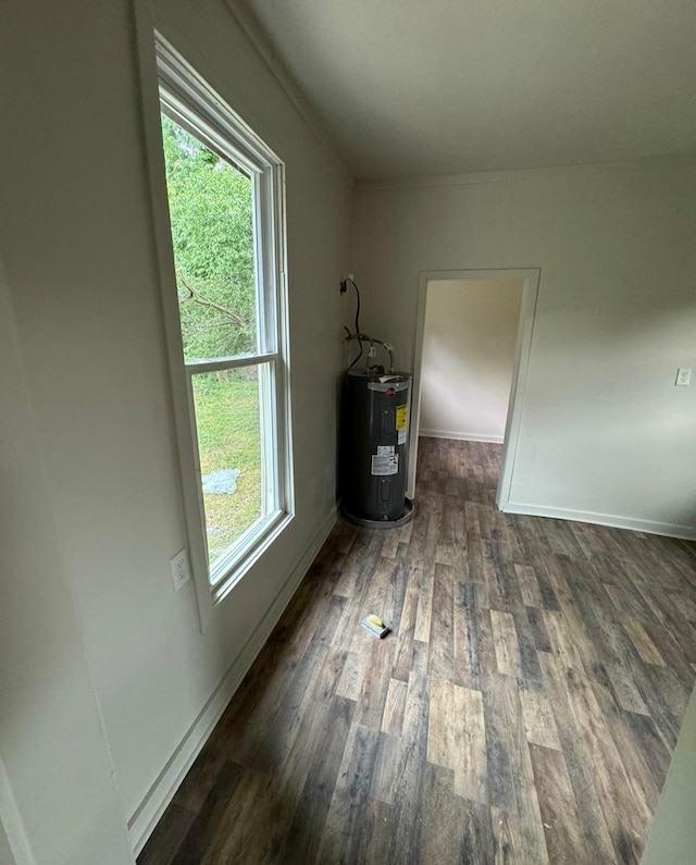 empty room with water heater, a healthy amount of sunlight, and dark hardwood / wood-style floors