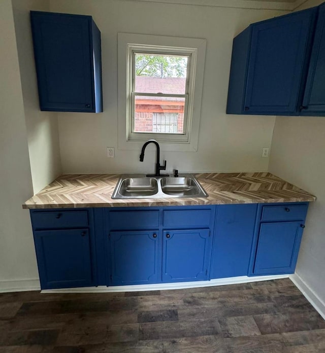 kitchen with dark wood-type flooring, blue cabinets, and sink