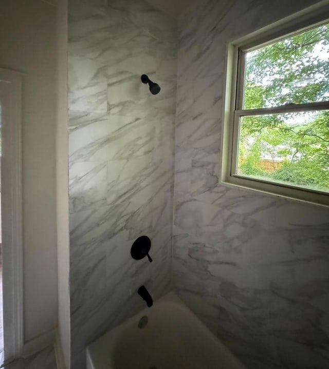 bathroom with a wealth of natural light and tiled shower / bath