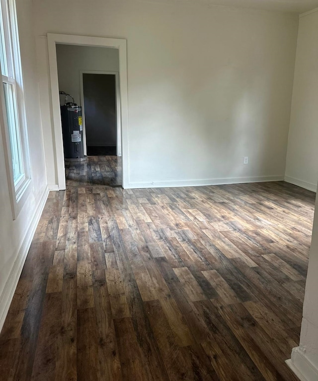 empty room featuring dark hardwood / wood-style flooring and water heater