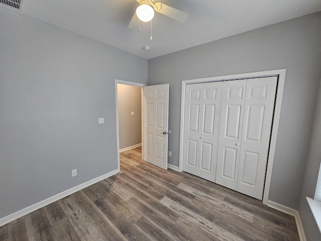 unfurnished bedroom featuring wood finished floors, baseboards, a closet, and ceiling fan