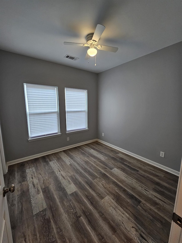 empty room with visible vents, a ceiling fan, dark wood-type flooring, and baseboards