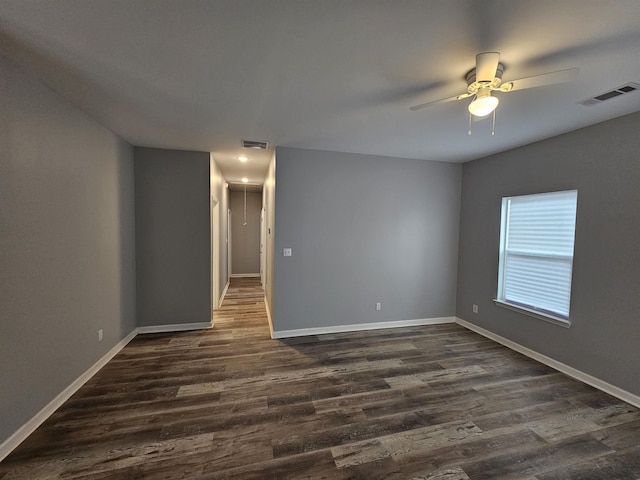 unfurnished room with dark wood finished floors, visible vents, and baseboards