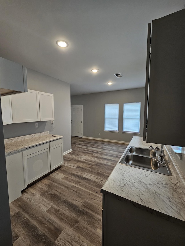 kitchen with visible vents, a sink, baseboards, white cabinetry, and dark wood-style flooring