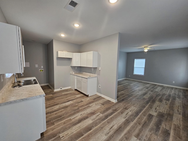 kitchen featuring dark wood-style floors, visible vents, a sink, light countertops, and white cabinets