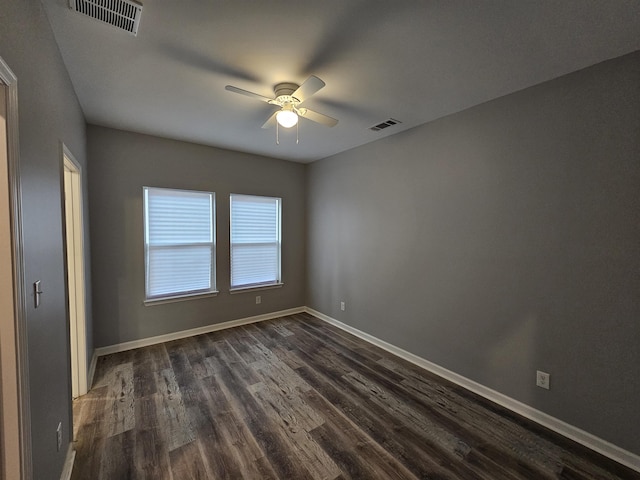 spare room featuring dark wood-style floors, visible vents, a ceiling fan, and baseboards