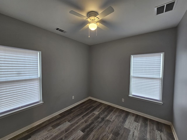 empty room with dark wood-style floors, visible vents, ceiling fan, and baseboards