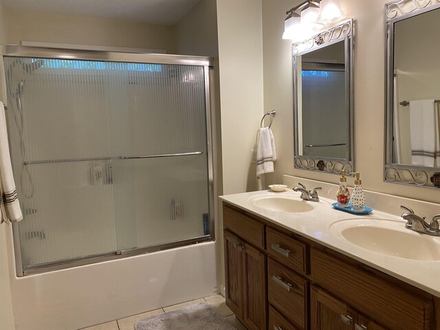 bathroom featuring tile patterned flooring, vanity, and combined bath / shower with glass door