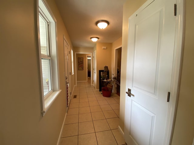 hall with light tile patterned flooring and a textured ceiling