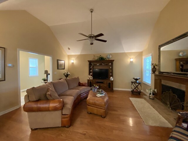 living room with hardwood / wood-style flooring, ceiling fan, and lofted ceiling