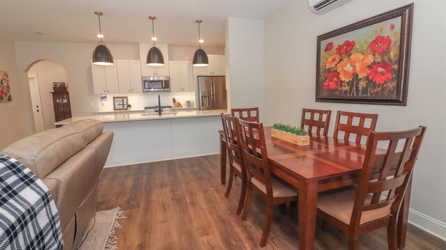 dining space featuring a wall mounted air conditioner and dark hardwood / wood-style floors