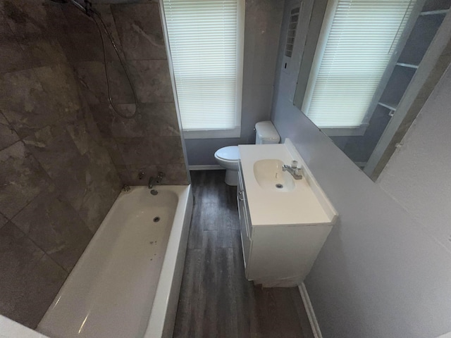 bathroom with shower / bathtub combination, toilet, vanity, wood finished floors, and baseboards