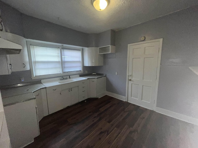 kitchen with baseboards, white cabinetry, light countertops, and dark wood finished floors