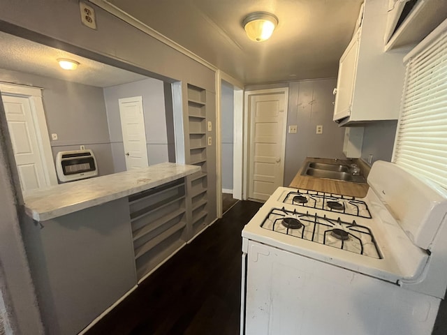 kitchen with white range with gas stovetop, heating unit, light countertops, white cabinetry, and a sink