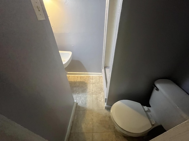 bathroom with toilet, tile patterned flooring, and baseboards