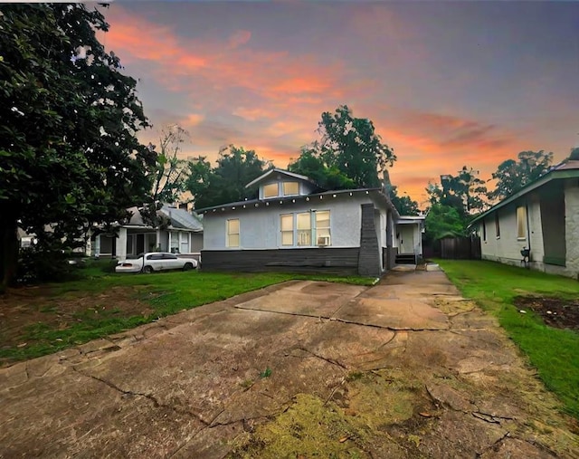 bungalow-style house with a lawn and stucco siding