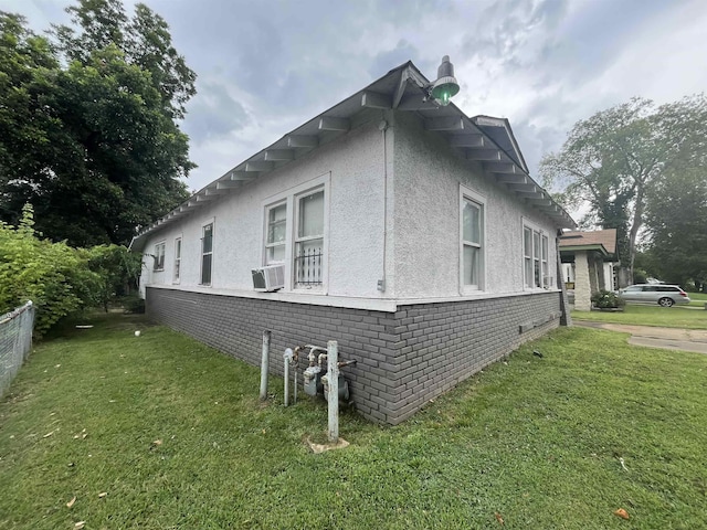 view of side of property with a yard, brick siding, cooling unit, and stucco siding