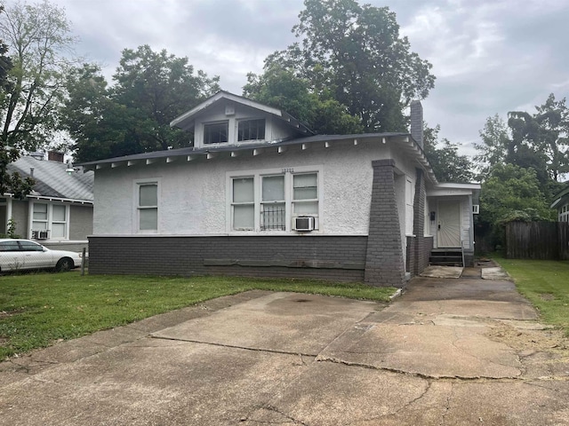 view of side of property featuring entry steps, brick siding, cooling unit, a yard, and stucco siding