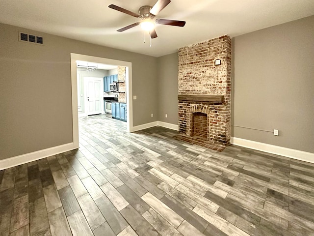 unfurnished living room with brick wall, a brick fireplace, ceiling fan, and hardwood / wood-style floors