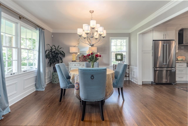 dining room featuring dark wood-type flooring, ornamental molding, and a notable chandelier