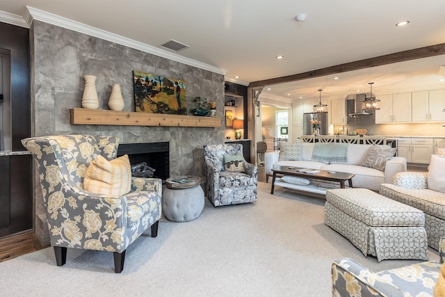 carpeted living room featuring an inviting chandelier, crown molding, and a premium fireplace